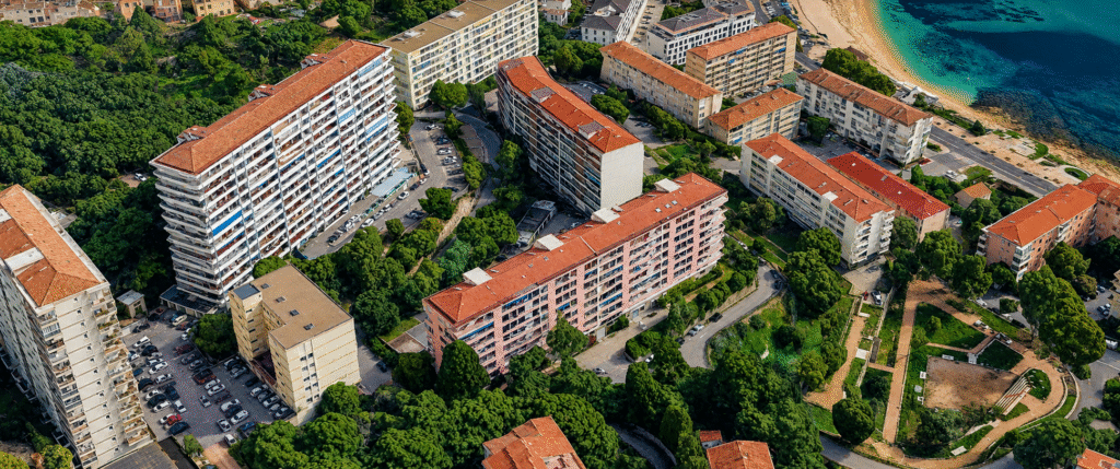 Vue aérienne du quartier Parc Berthault à Ajaccio, avec ses résidences collectives, ses espaces verts et la mer Méditerranée en arrière-plan.