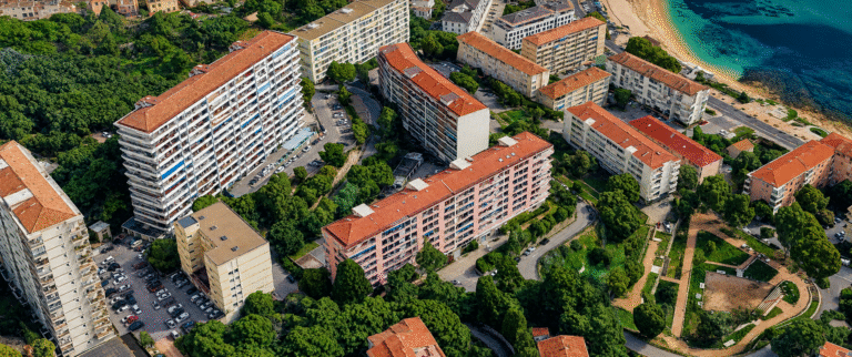 Vue aérienne du quartier Parc Berthault à Ajaccio, avec ses résidences collectives, ses espaces verts et la mer Méditerranée en arrière-plan.